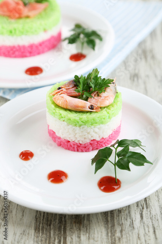 Colored rice on plates on napkin on wooden table
