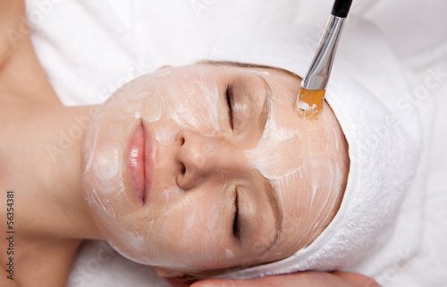 Spa therapy for woman receiving facial mask at beauty salon