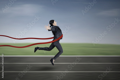 Asian businesswoman crossing finish line