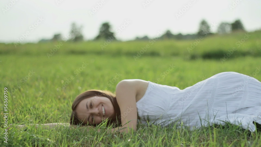 Beautiful young woman lying on green grass Beautiful young woman lying on green grass