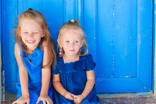 Closeup of Little adorable girls sitting near old blue door in