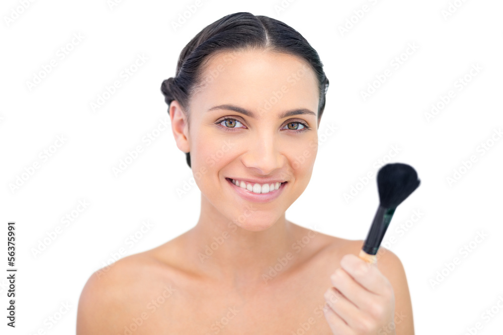 Smiling natural model holding a powder brush Smiling natural model holding a powder brush