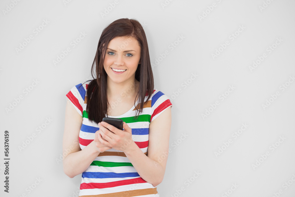 Smiling girl using her mobile phone looking at camera Smiling girl using her mobile phone looking at camera