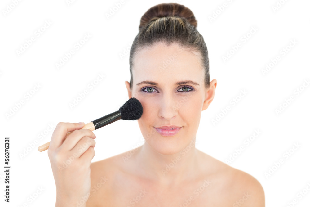 Happy woman using blusher brush