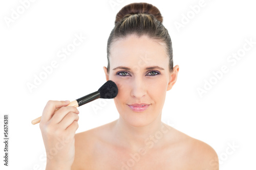 Happy woman using blusher brush