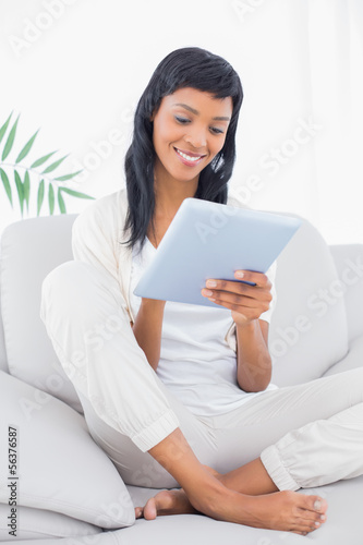 Relaxed black haired woman in white clothes using a tablet pc
