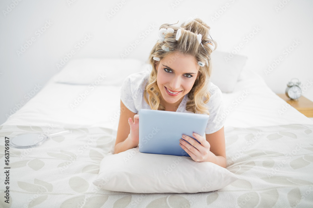 Smiling pretty blonde wearing hair curlers using tablet pc Smiling pretty blonde wearing hair curlers using tablet pc