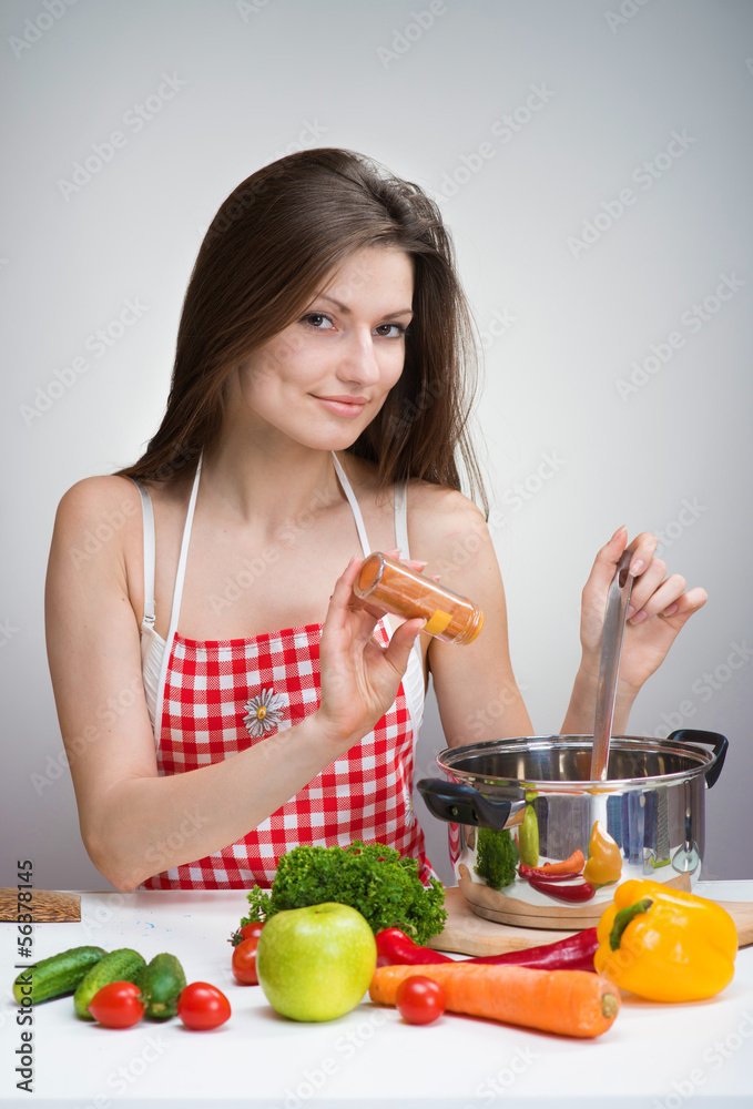 Smiling woman in an apron seasoning soup with paprika Smiling woman in an apron seasoning soup with paprika