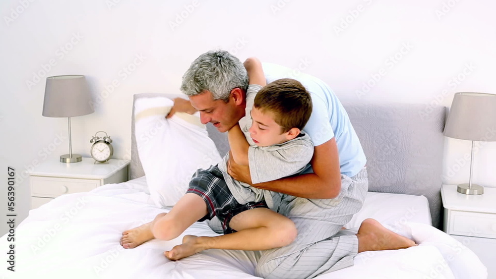 Father and son having a pillow fight in the bed Father and son having a pillow fight in the bed