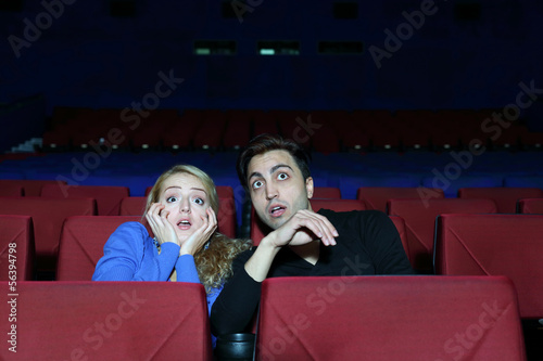 Young man and woman watch movie and very much afraid