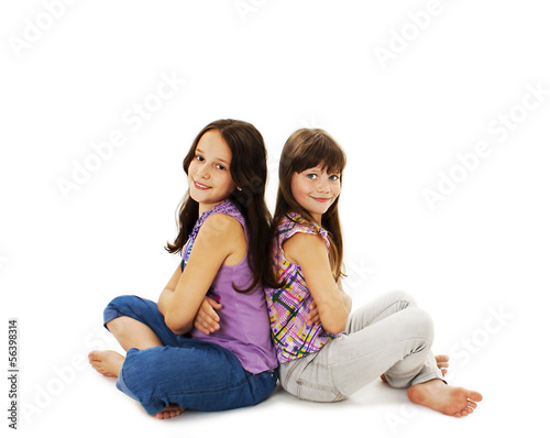 Portrait of a two little girls sitting back to back and smiling
