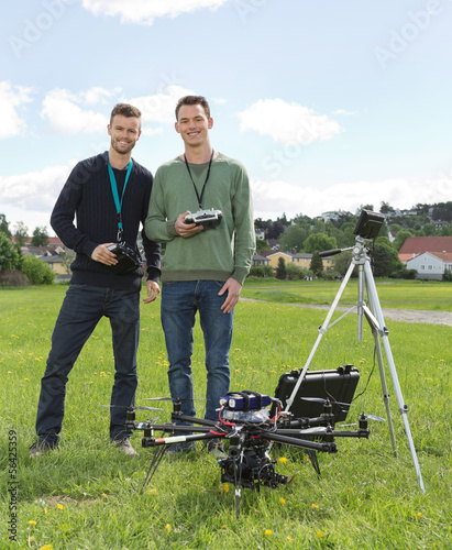 Engineers Standing By UAV Helicopter And Tripod
