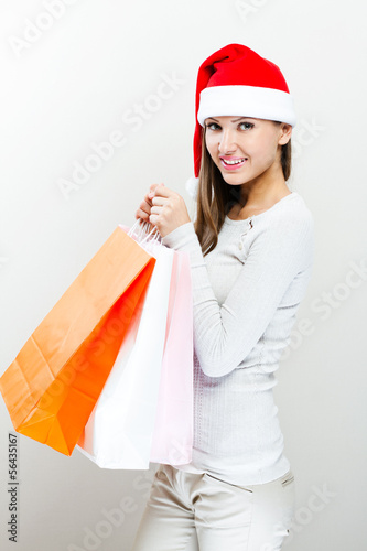 Christmas Santa hat woman with shopping bags. Smiling happy gir