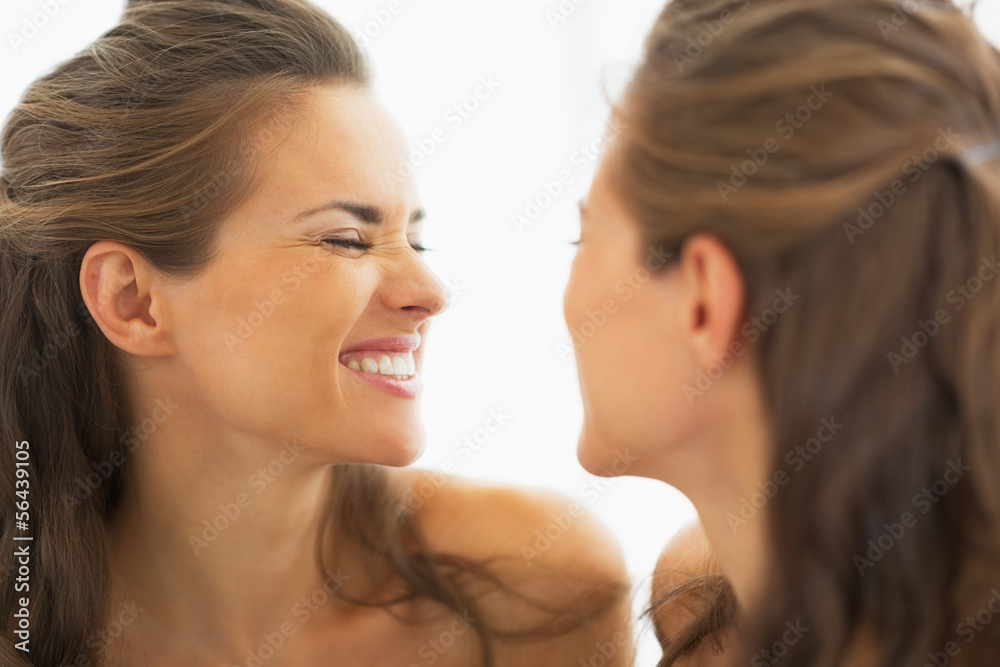 Happy young woman making funny face in mirror Happy young woman making funny face in mirror