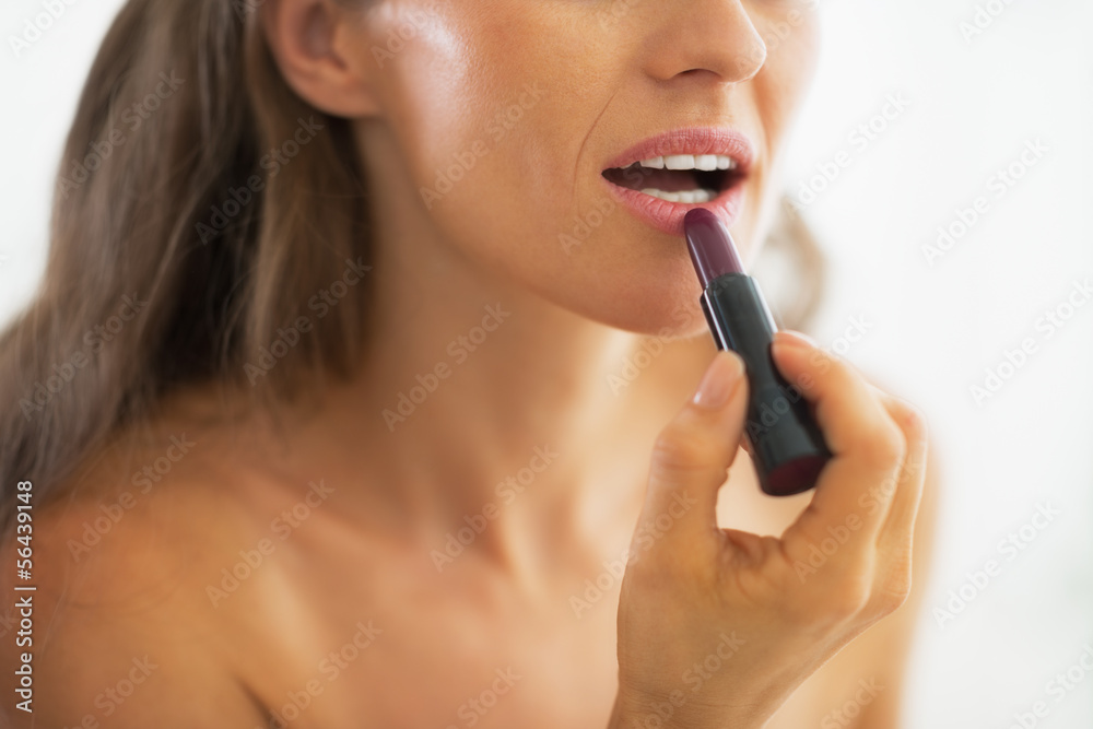 Closeup on woman applying lipstick in bathroom Closeup on woman applying lipstick in bathroom