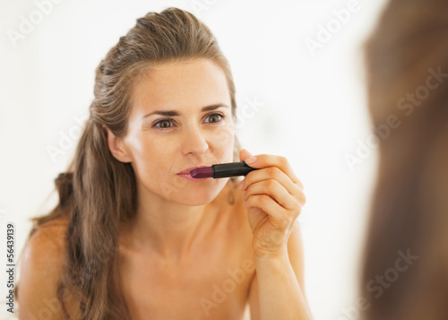 Woman choosing lipstick in bathroom