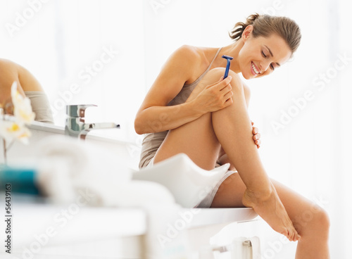 Happy woman checking legs after shaving