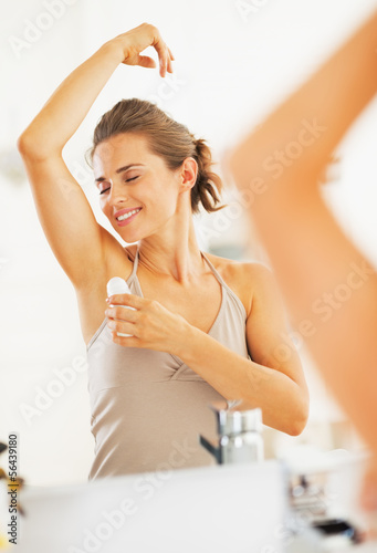 Happy woman enjoying freshness after applying roller deodorant 