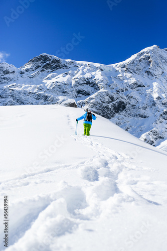 Freeride, man with skis climbs to the top