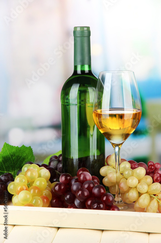 Wine bottle and glass of wine on tray, on bright background