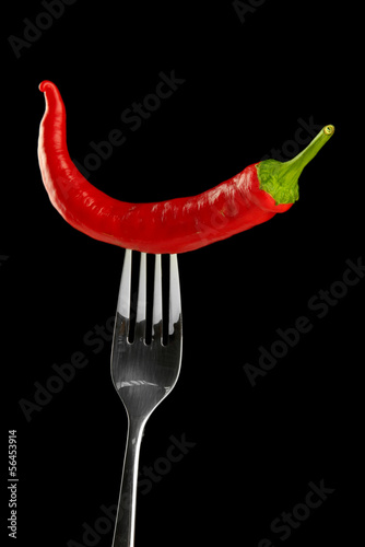 Red hot chili pepper on fork, isolated on black © Africa Studio