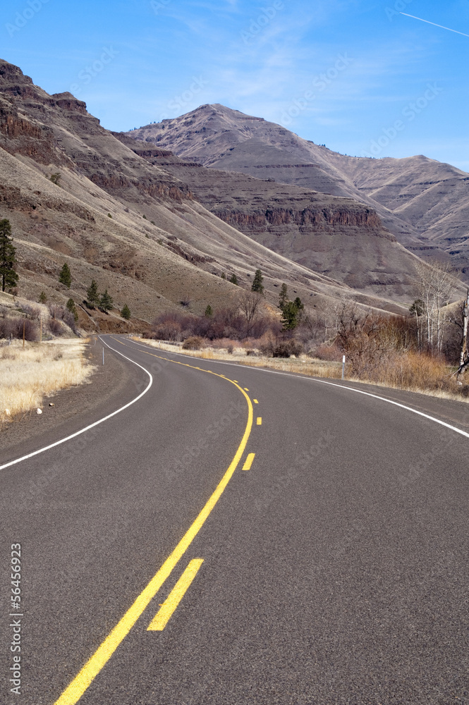 Naklejka premium Lonely Two Lane Divided Highway Cuts Through Dry Landscape
