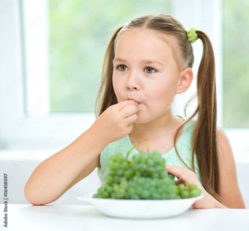 Cute little girl is eating green grapes Cute little girl is eating green grapes