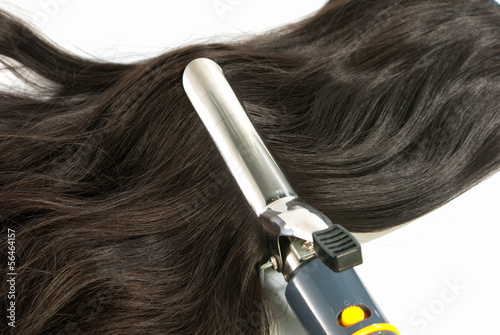 Electric curling iron and hair on white background
