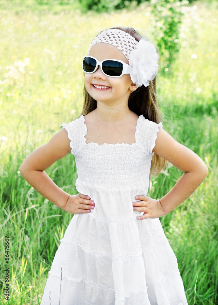 Cute smiling little girl in sunglasses on the meadow Cute smiling little girl in sunglasses on the meadow