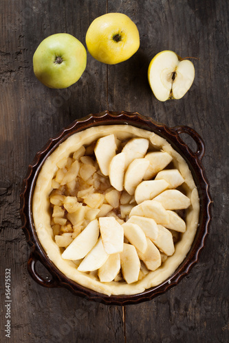 Apple pie and apples on a wooden backgroun.
