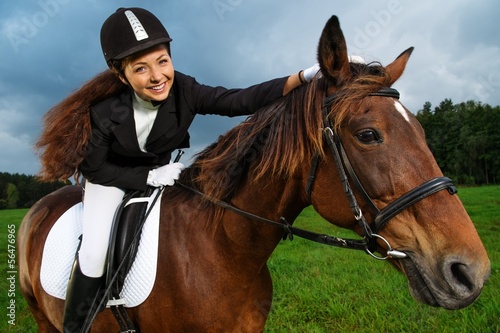 Beautiful smiling girl sitting on a horse outdoors