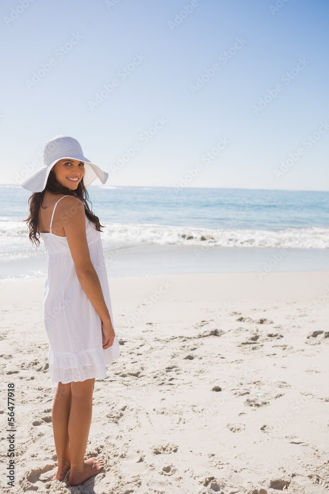 Brunette in white sunhat and dress looking over her shoulder at