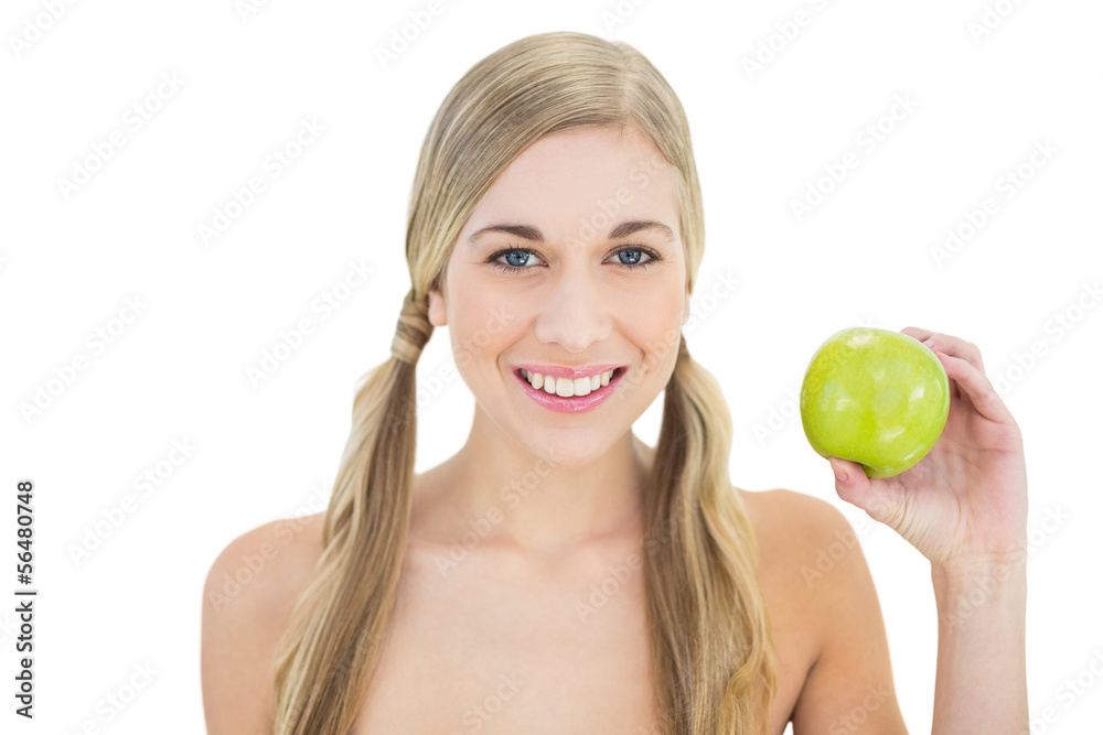 Pleased young blonde woman holding a green apple Pleased young blonde woman holding a green apple