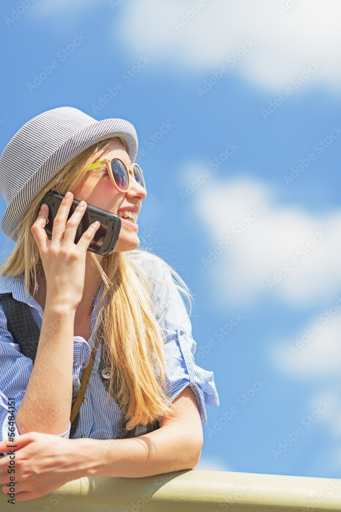 Fototapeta premium Smiling girl talking mobile phone and looking on copy space