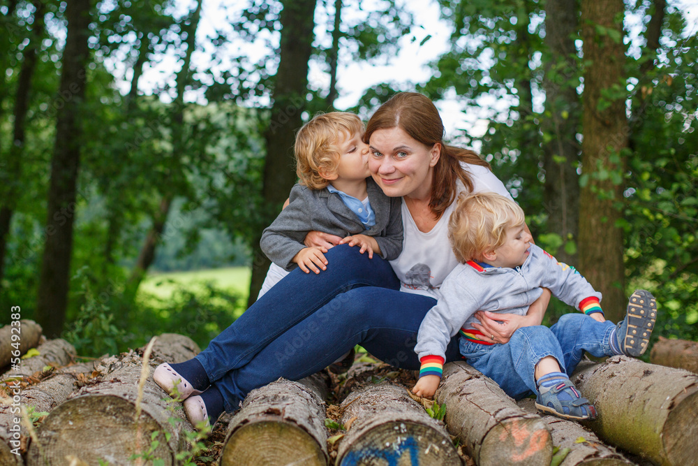 Fototapeta premium Young mother and two little boys having fun in summer forest.