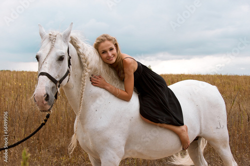 girl in the black dress is riding on horse