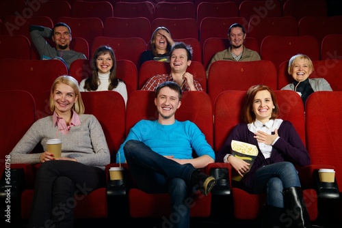 Group of smiling people watching movie in cinema