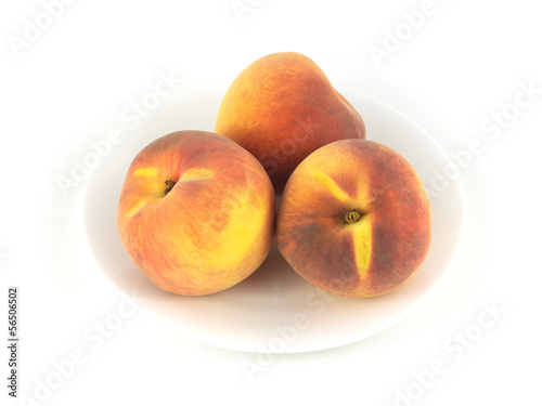 Three fresh Peaches on plate isolated on white close up