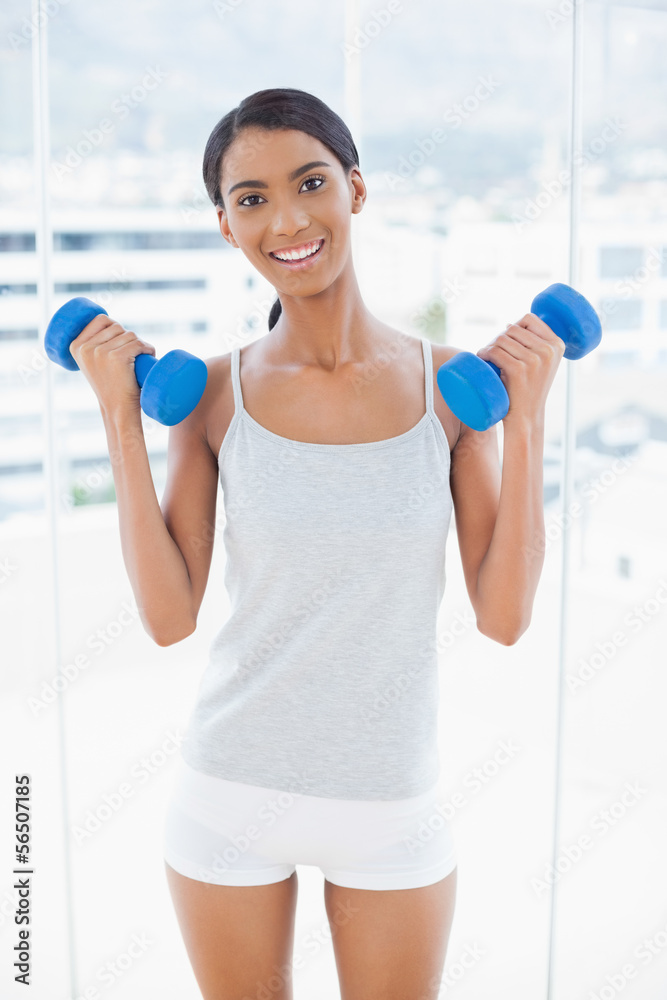 Happy sporty model exercising with dumbbells