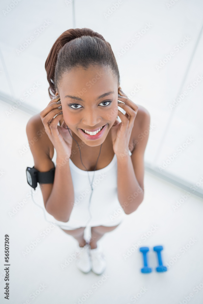 Naklejka premium High angle view of smiling fit woman listening to music