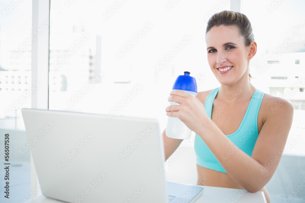 Smiling blonde woman in sportswear holding flask Smiling blonde woman in sportswear holding flask