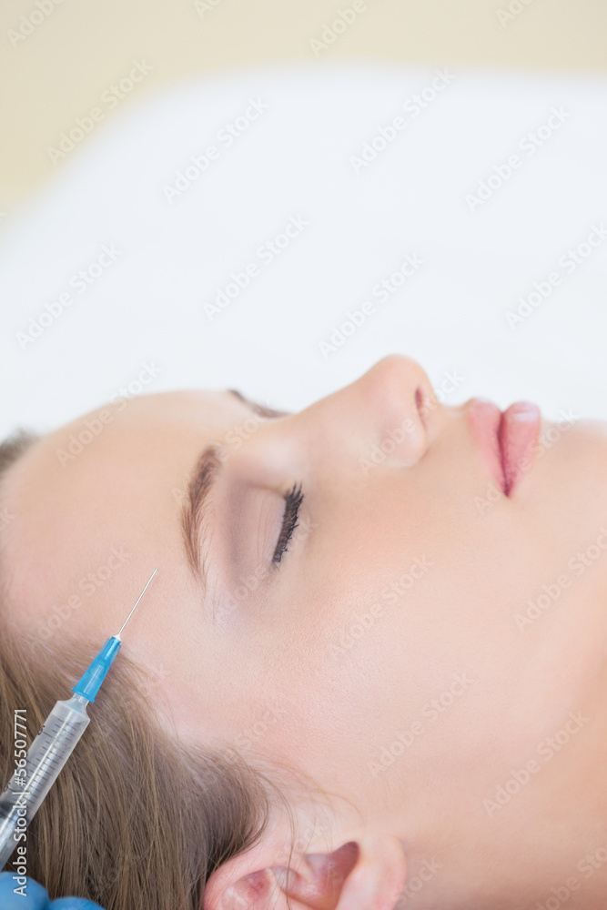 Surgeon making injection on peaceful woman lying Surgeon making injection on peaceful woman lying