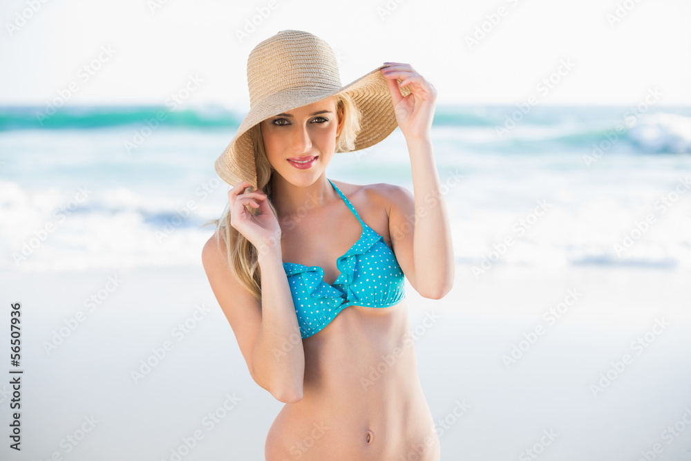 Cheerful gorgeous blonde in bikini wearing straw hat