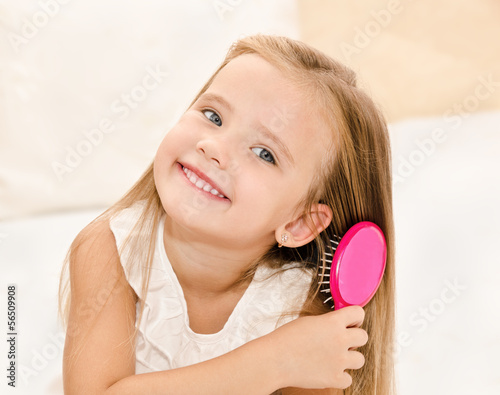Portrait of smiling little girl brushing her hair