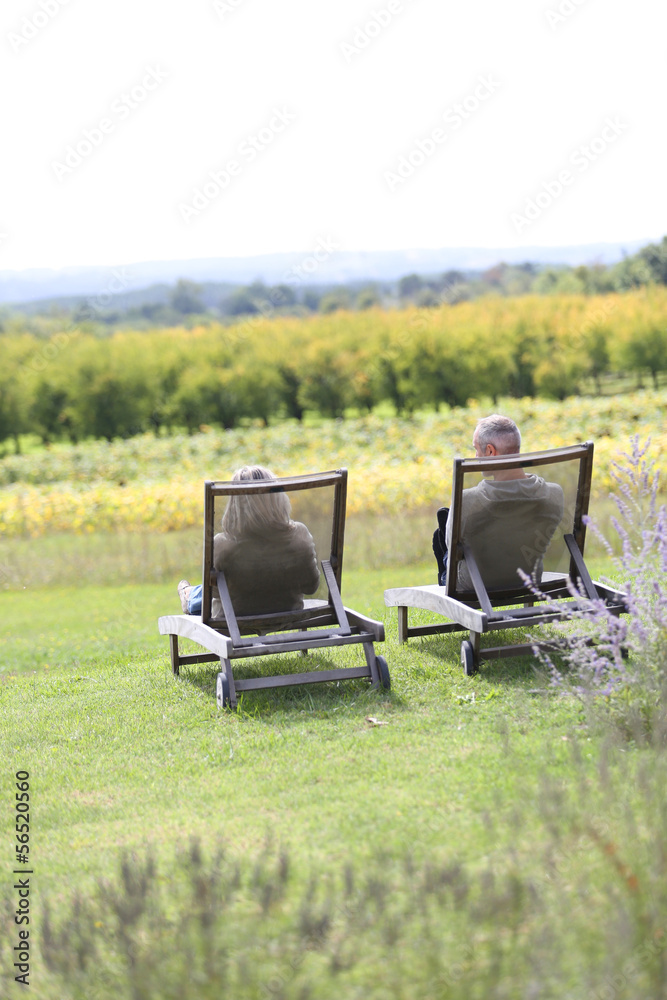 Fototapeta premium Senior people relaxing in long chairs in countryside