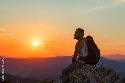 tourist sits in the mountains enjoying the sunrise