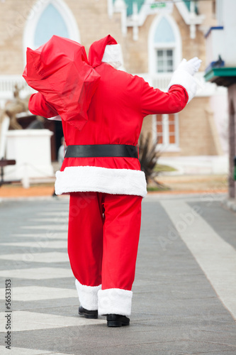 Santa Claus With Bag Waving While Walking In Courtyard