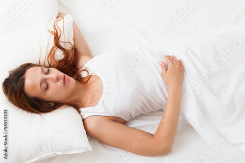 girl sleeping on a white pillow in bed at home