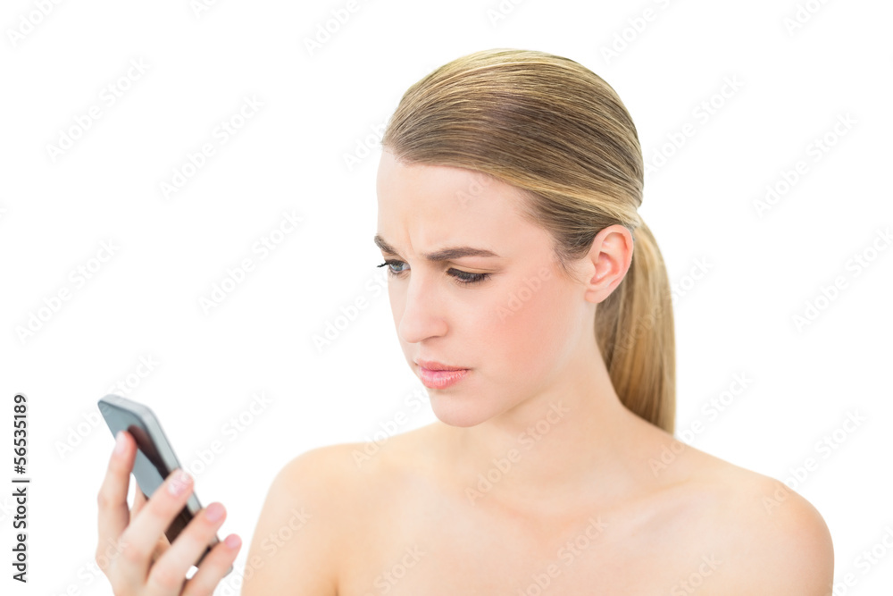 Frowning attractive blonde looking at her smartphone Frowning attractive blonde looking at her smartphone