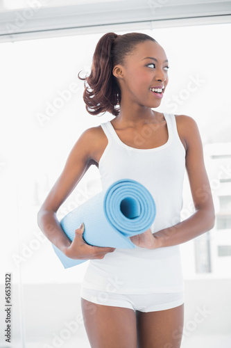 Sporty woman holding exercise mat